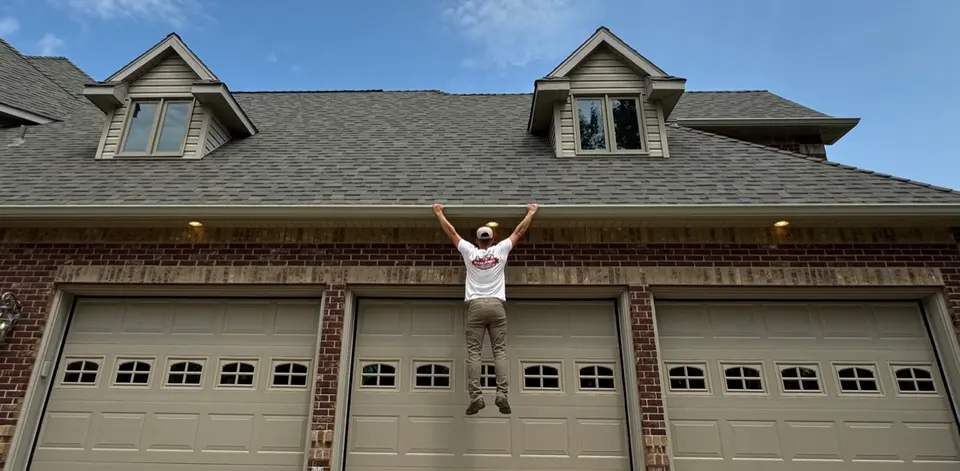 Badlands installer hanging by his hands from an installed gutter guard