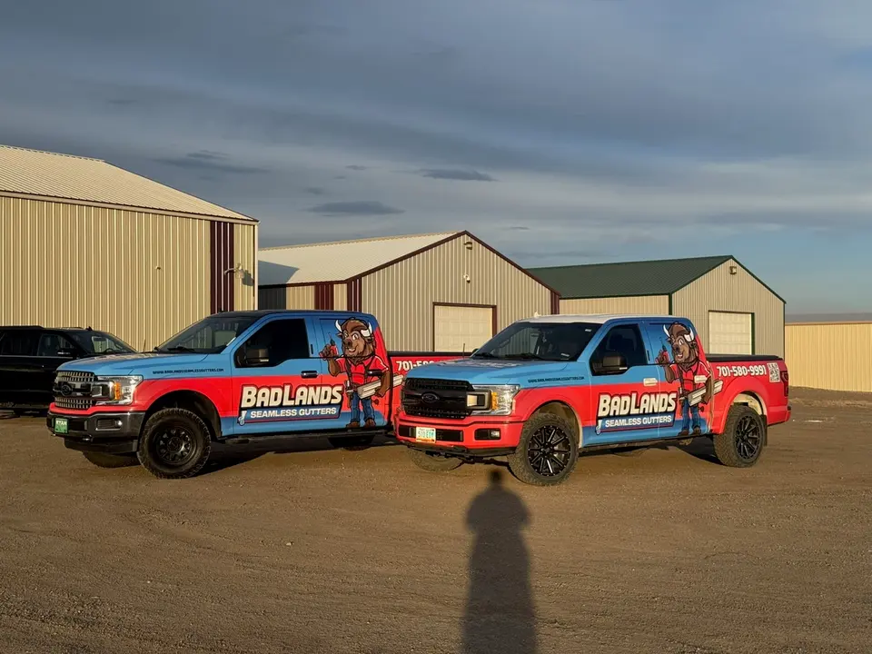Two Badlands branded gutter trucks parked at the shop