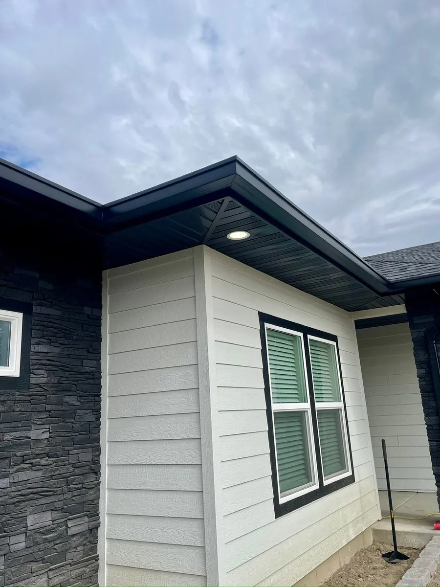 New house with white siding and black trim, eaves with no gutters